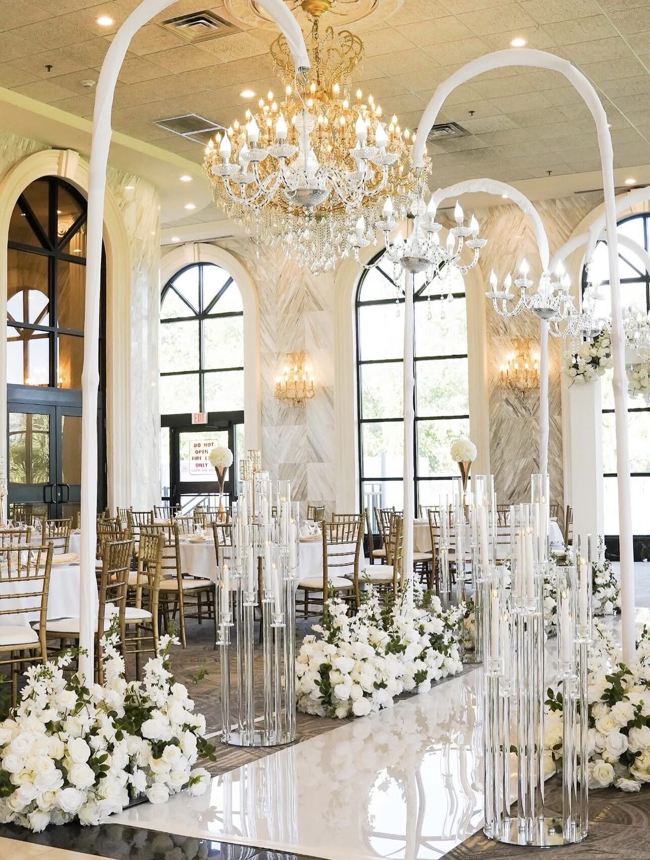Grand ballroom aisle with crystal candelabras beneath a gold chandelier