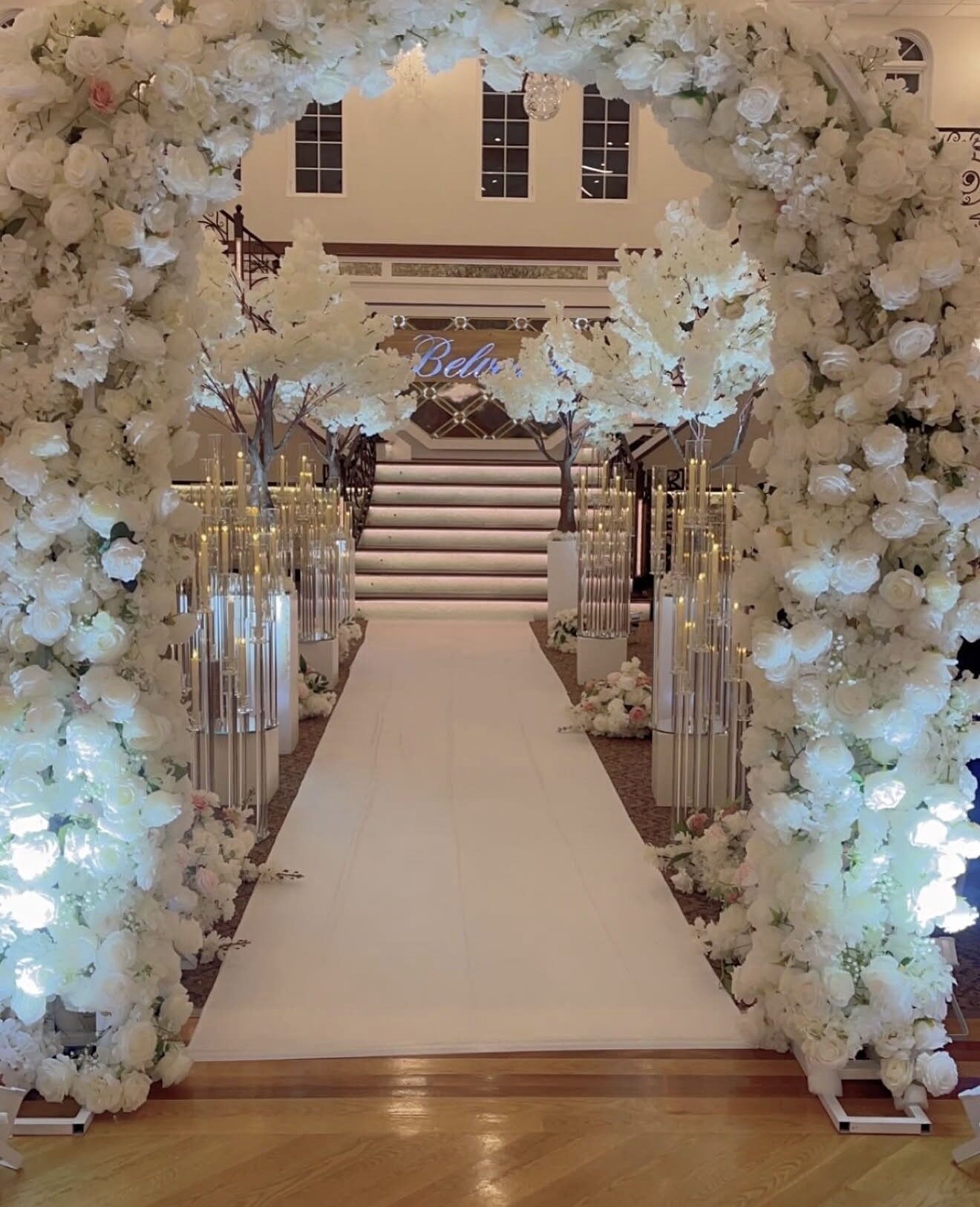 White rose floral archway entrance leading to a grand staircase