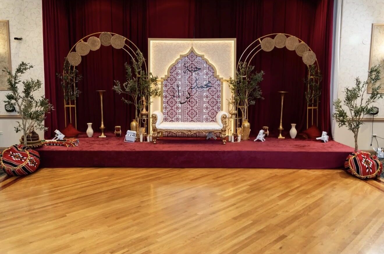 Moroccan-inspired stage with gold arches, burgundy drape and olive trees
