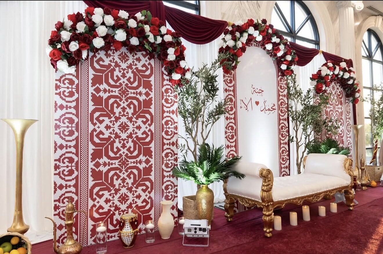 Red and white tatreez backdrop with roses and gold accents