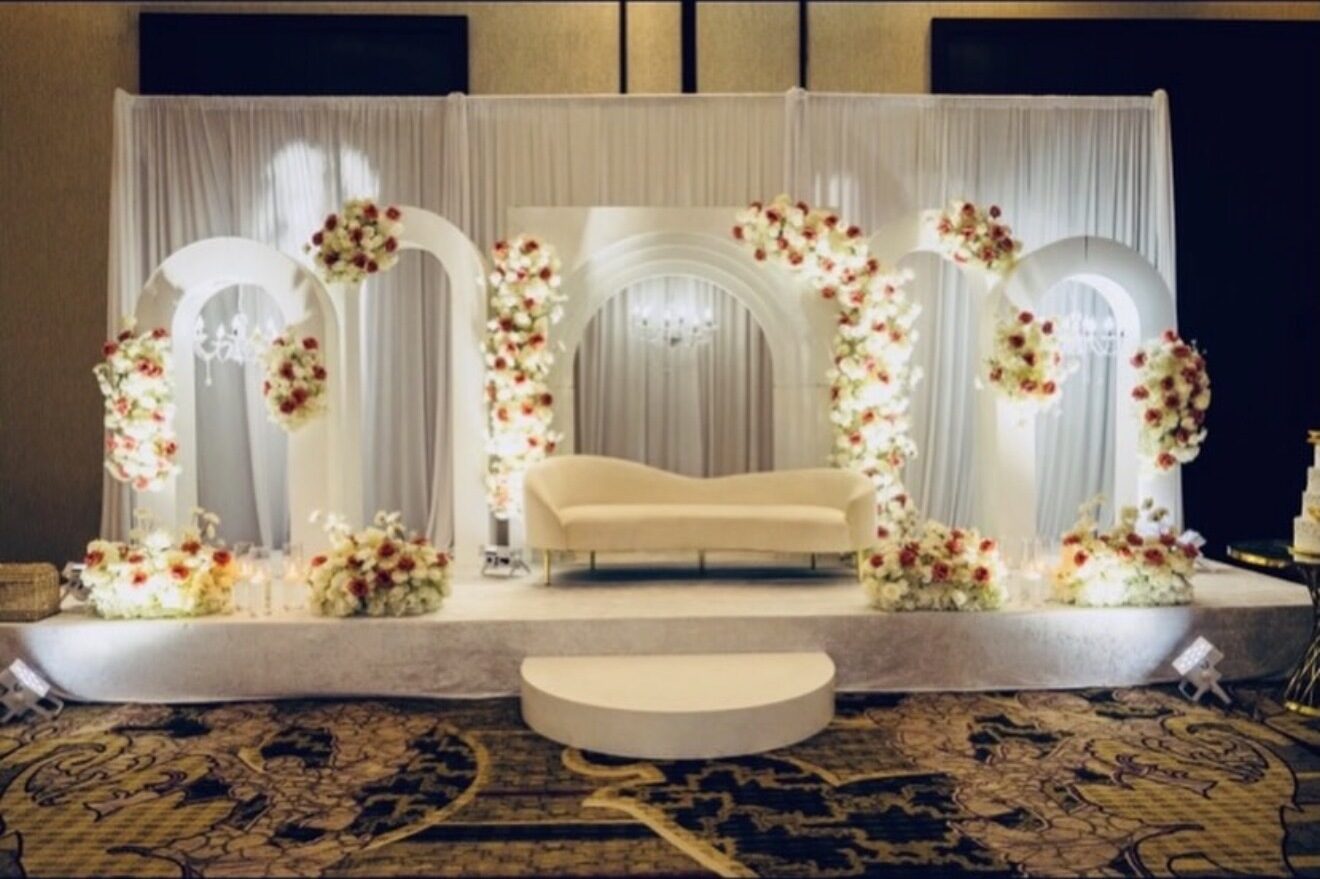 White and red floral arches with a cream sofa on a reception stage